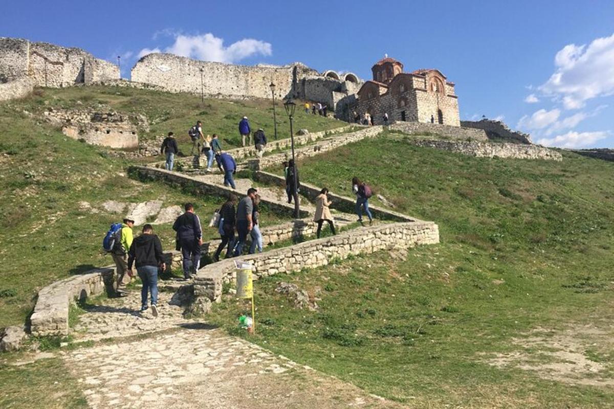 un grup de persones pujant un turó amb un castell