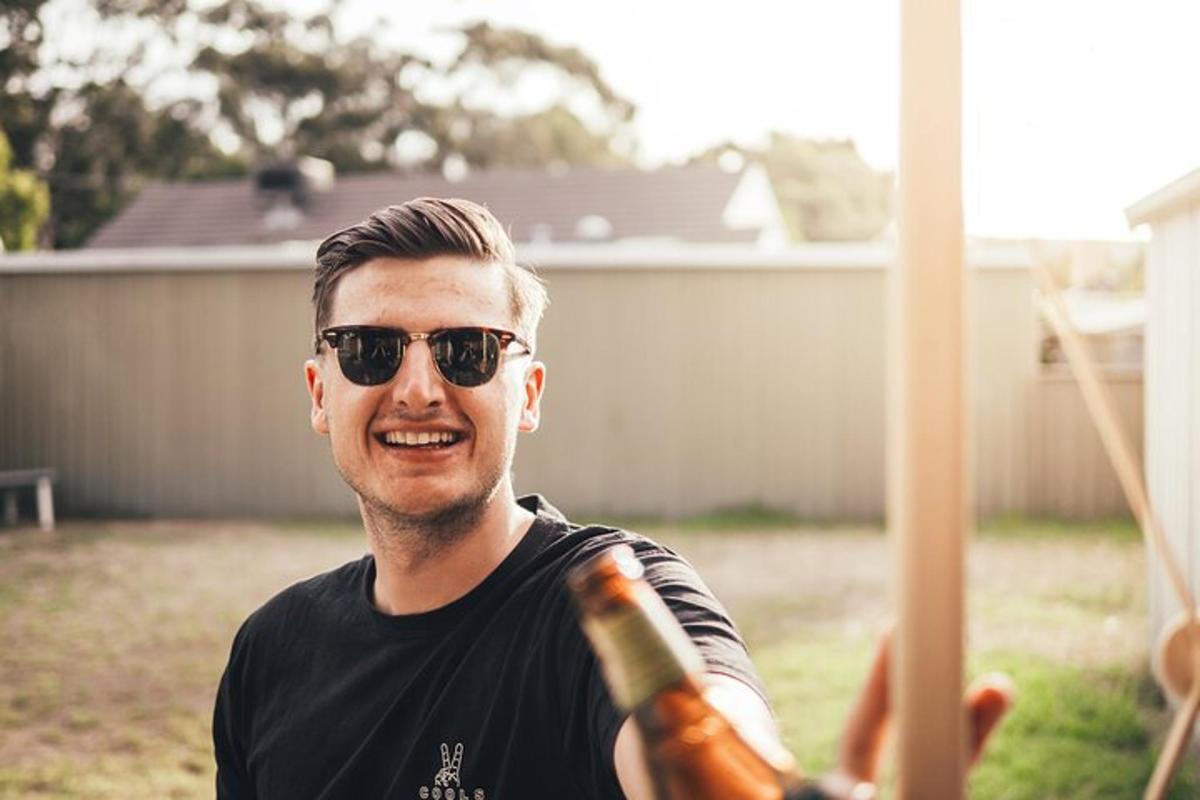 un uomo con occhiali da sole che tiene in mano una bottiglia di champagne