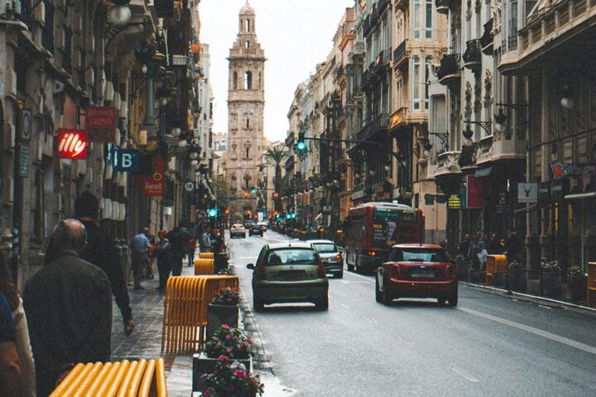 una strada cittadina trafficata con auto e una torre dell'orologio