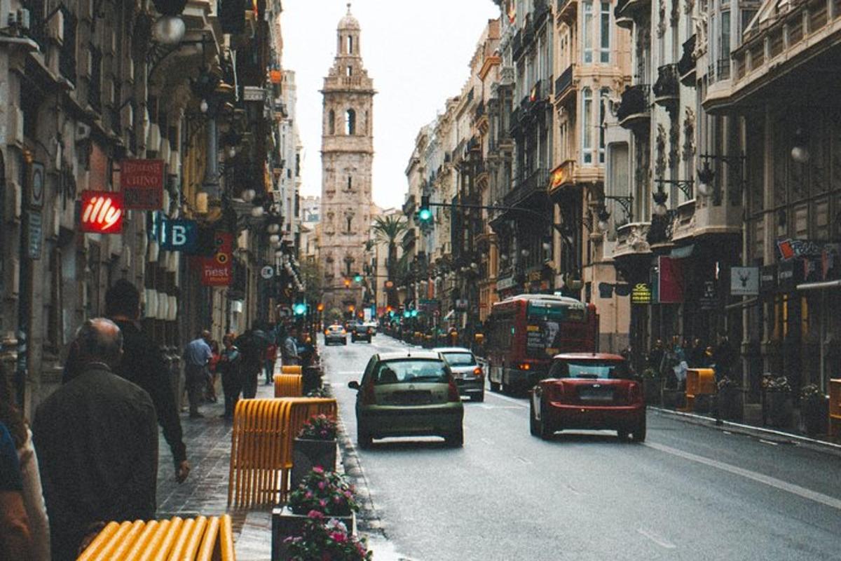 un carrer concorregut de la ciutat amb cotxes i una torre del rellotge