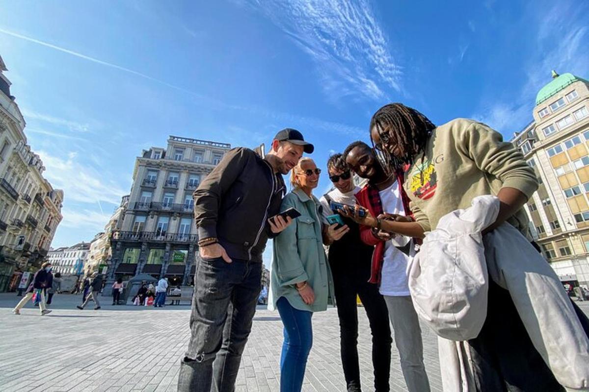 Un grupo de personas paradas en una calle mirando un teléfono celular.