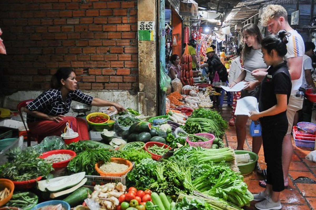 a group of people standing around a market with vegetables