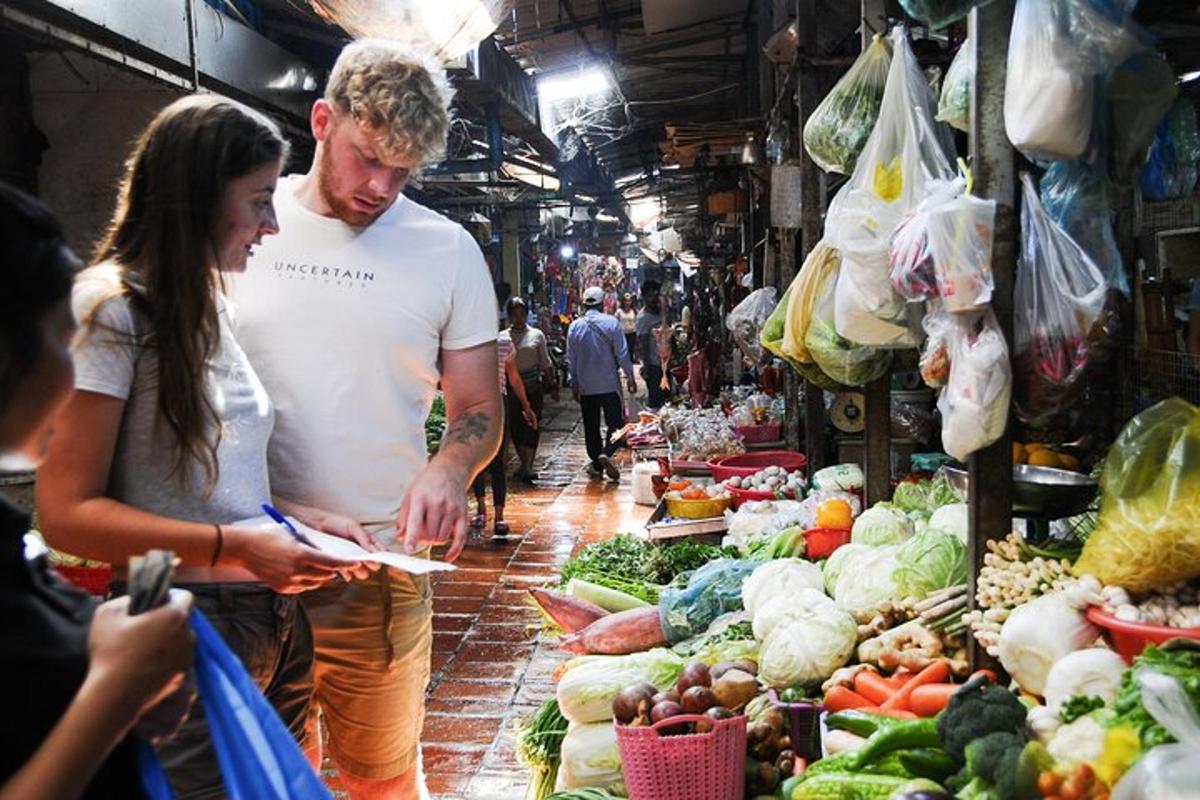 a man and woman standing in a market with vegetables