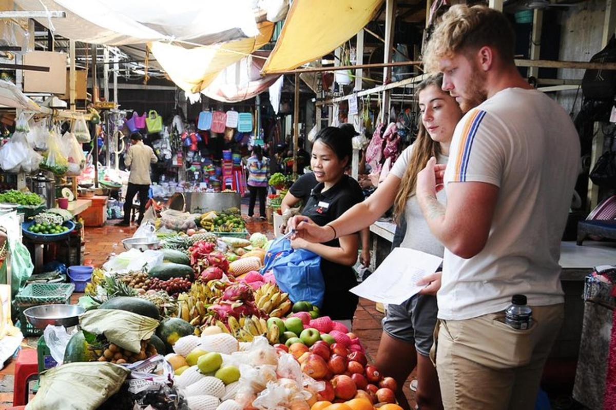 Un grupo de personas de pie en un mercado con frutas y verduras.