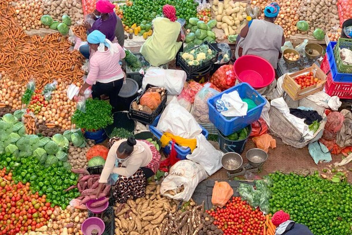 a group of people at a market with fruits and vegetables