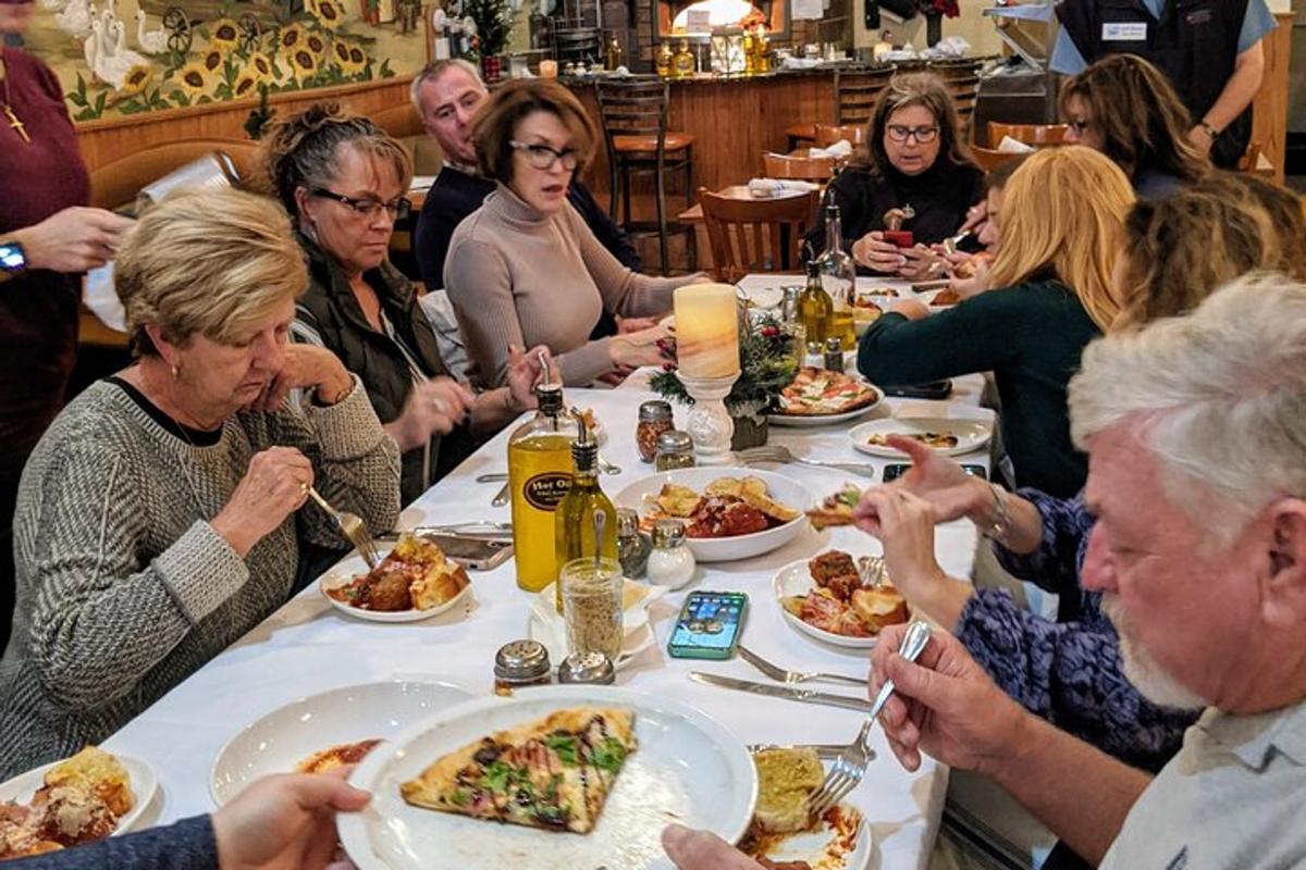 grupp inimesi istub laua taga ja sööb toitu