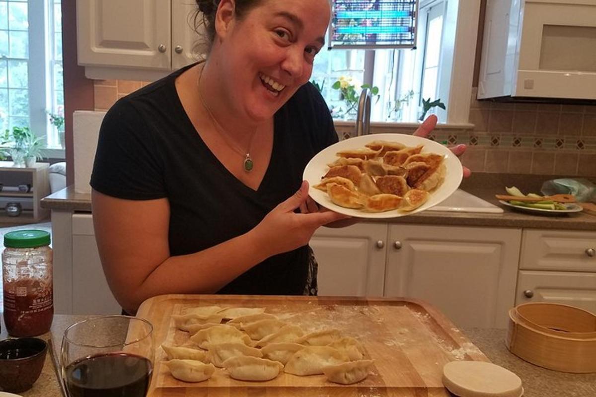 a woman holding a plate of dumplings in a kitchen