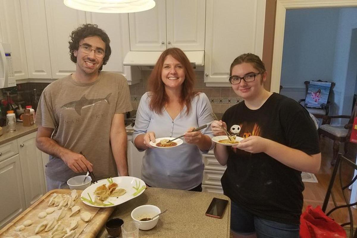 three people standing in a kitchen holding plates of food