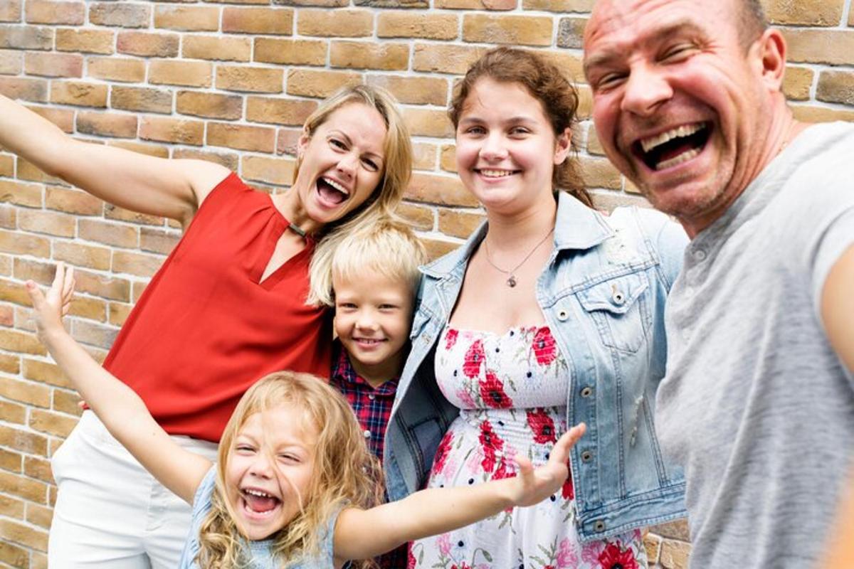 Fjölskylda poserar fyrir mynd fyrir framan múrsteinsvegg