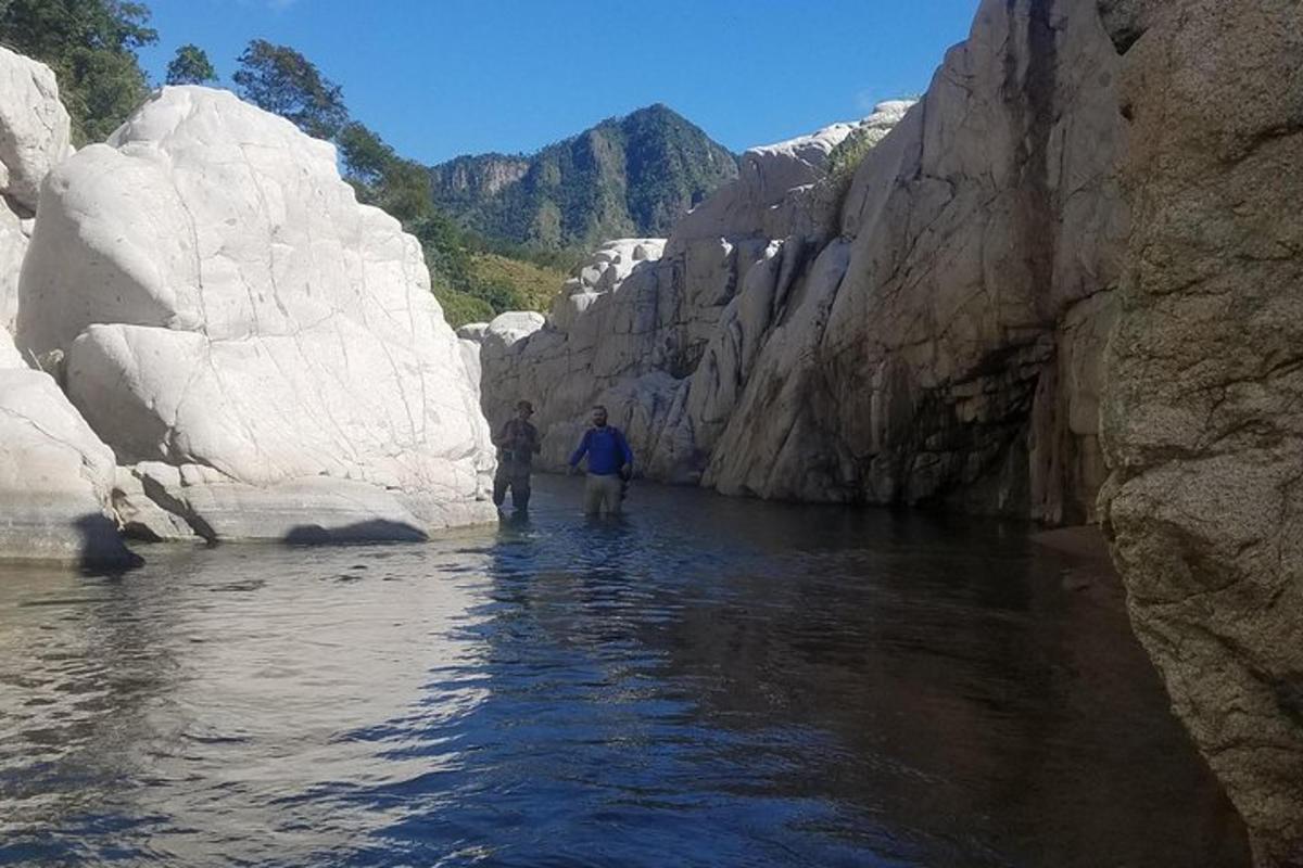 two people standing in a river between rocks