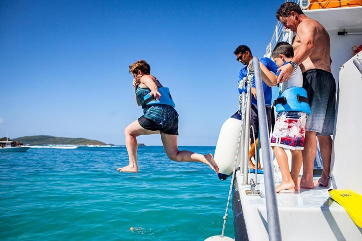 a group of people jumping off of a boat
