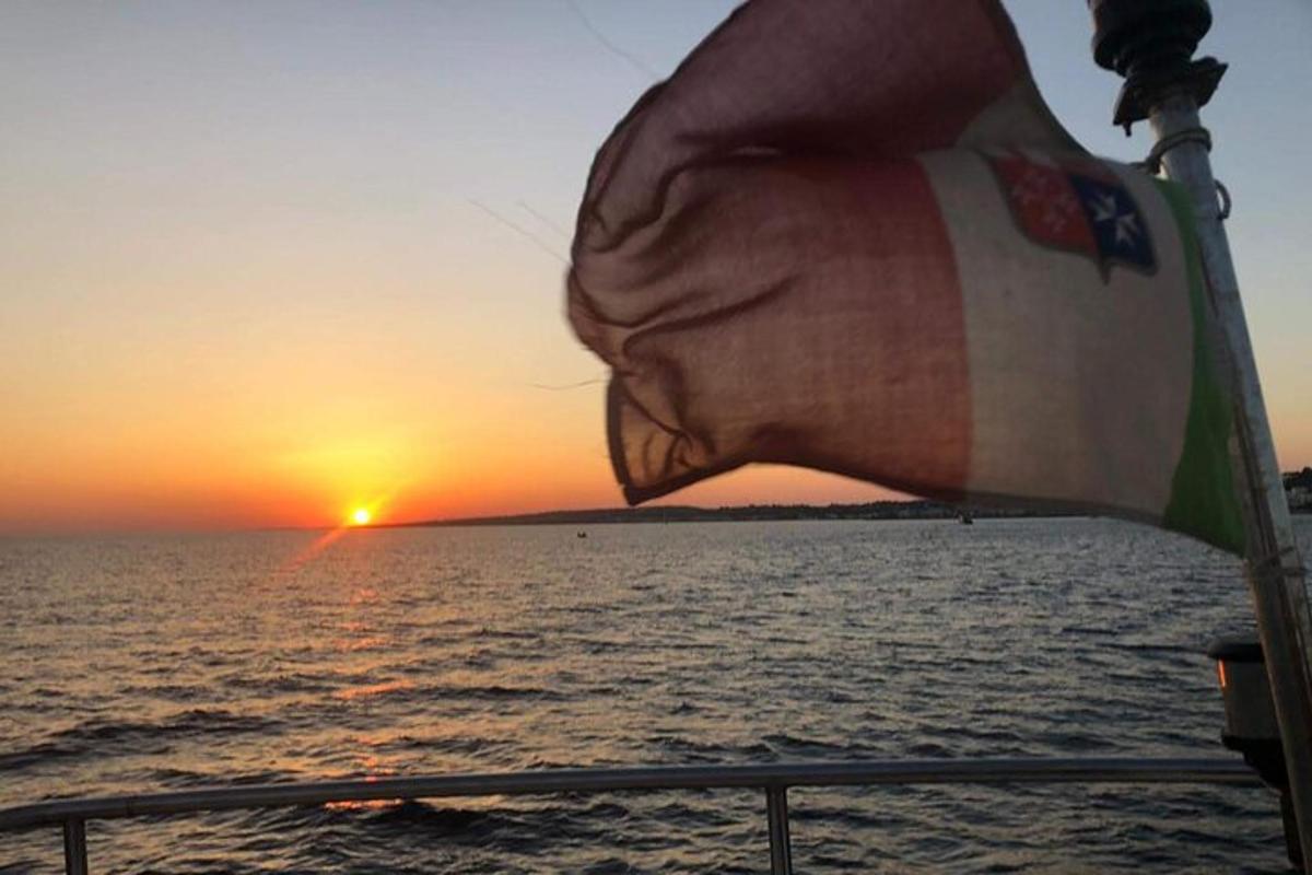una bandera en un creuer amb la posta de sol al fons