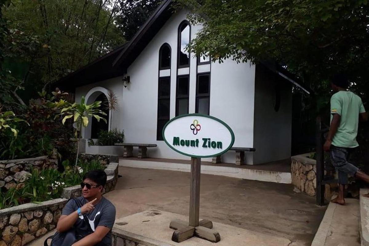 um homem sentado ao lado de uma placa em frente a uma casa
