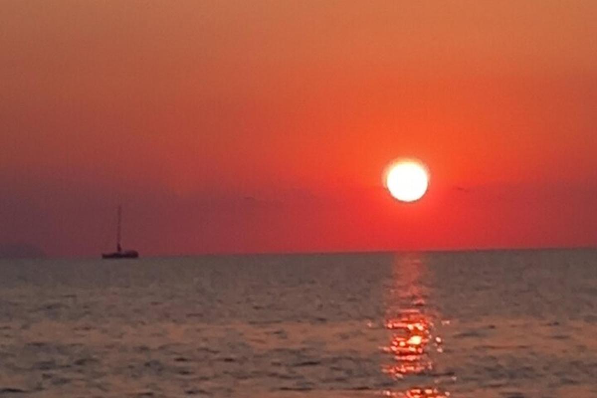 ein Sonnenuntergang über dem Meer mit einem Boot im Wasser