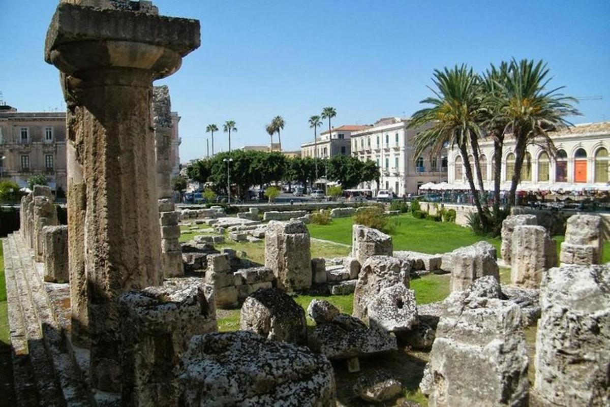 a group of ruins in front of a building with palm trees