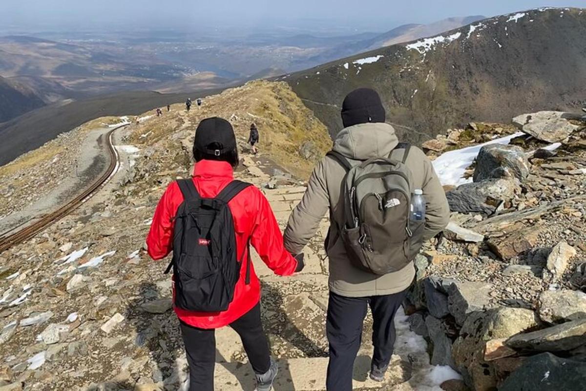 two people standing on top of a mountain holding hands