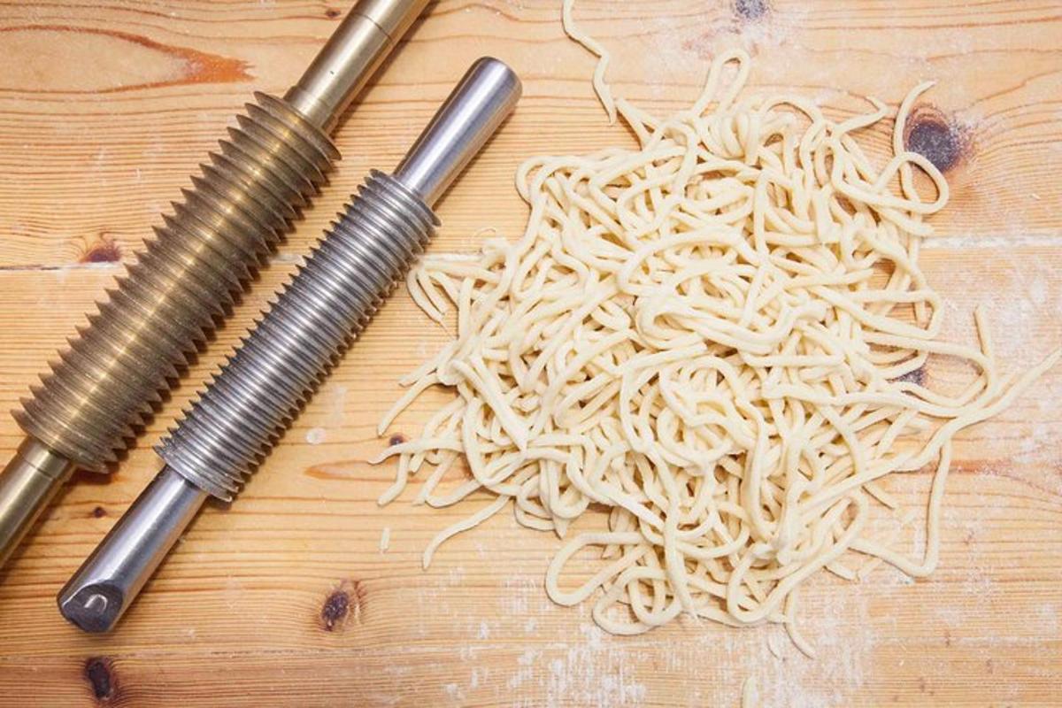 a pile of noodles on a wooden table with two knives