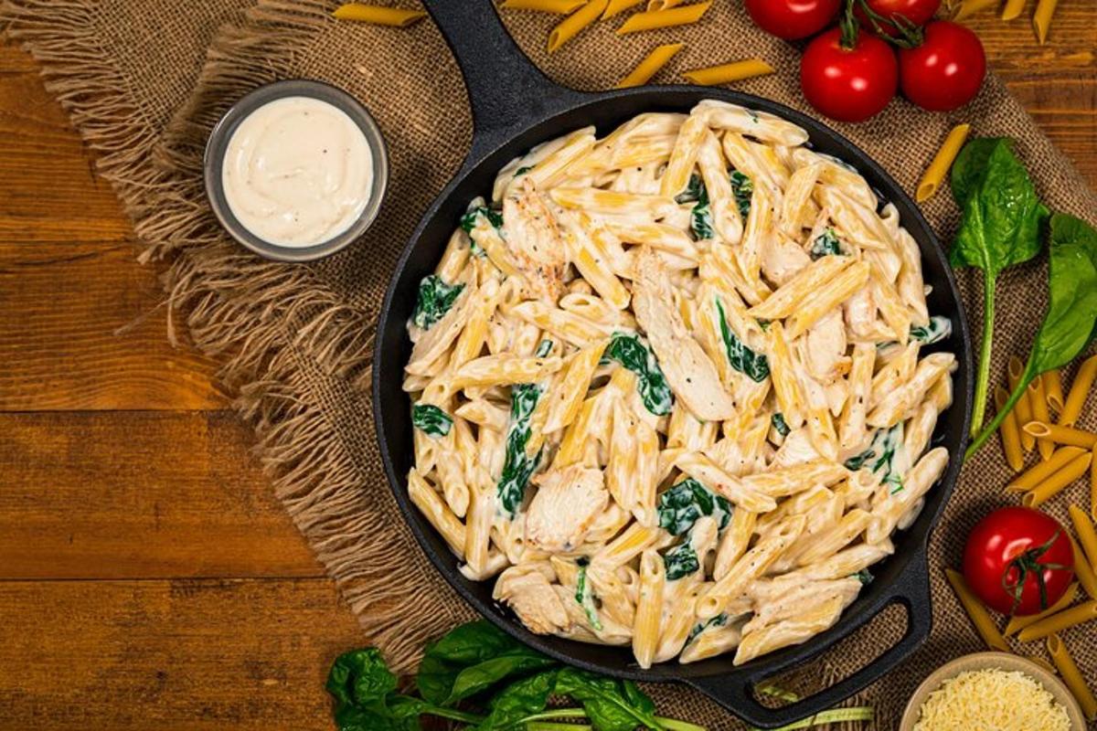 kuali pasta dengan ayam dan bayam di atas meja