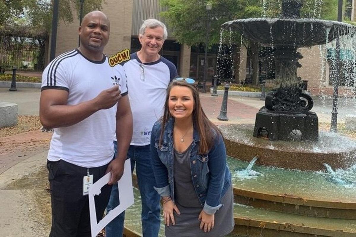 a group of three people standing in front of a fountain