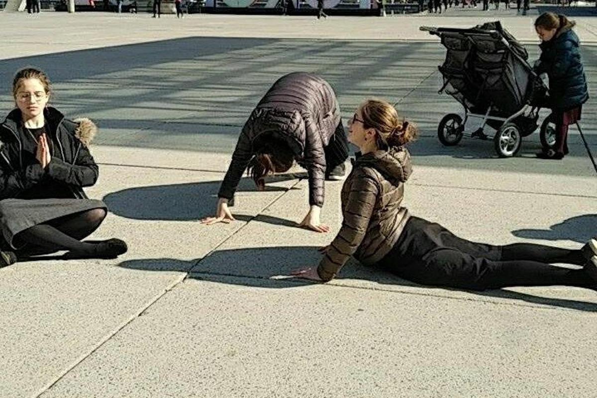 a woman is sitting on the ground on the sidewalk