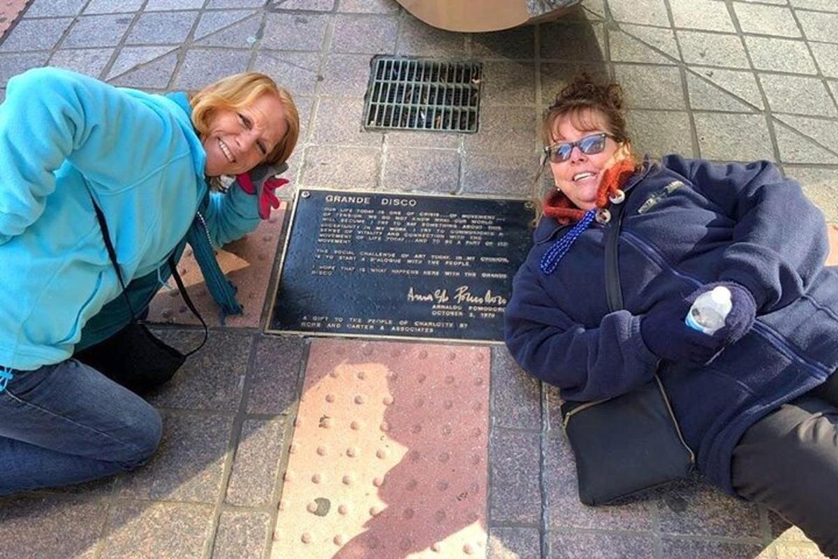 two women are standing next to a plaque on the ground