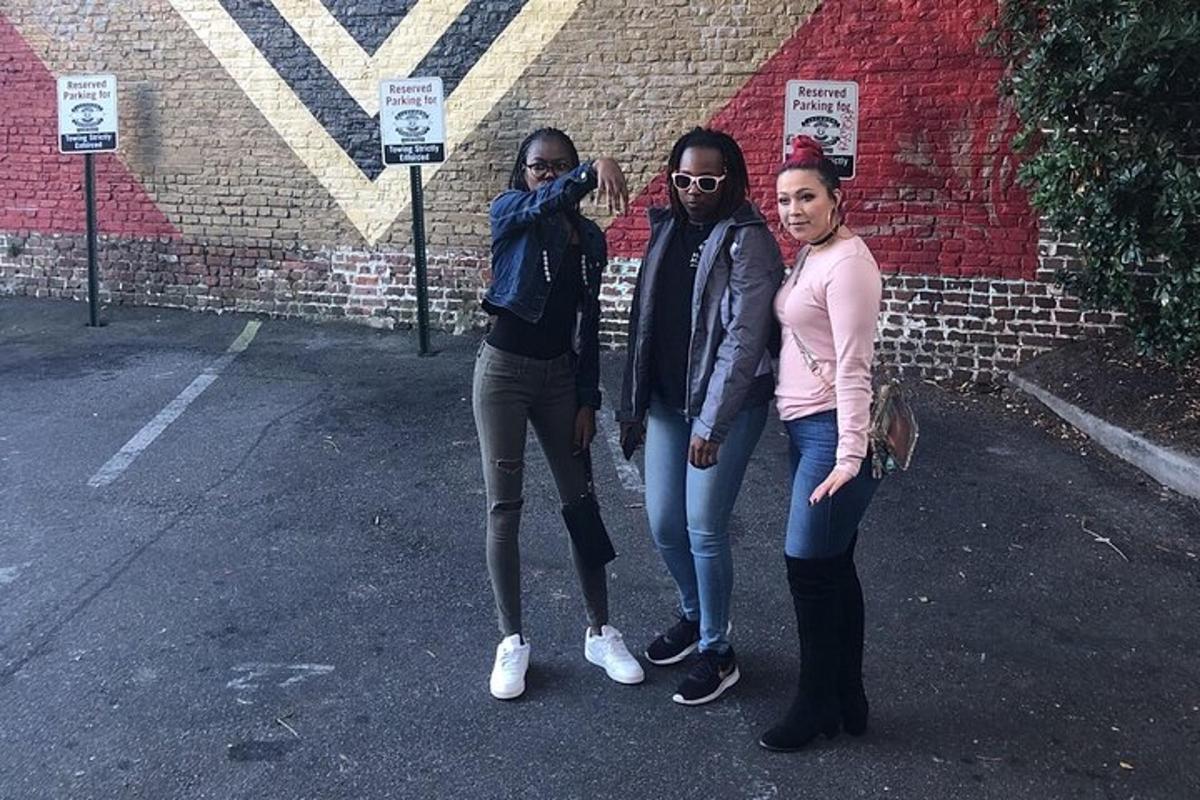 a group of three women standing next to a brick wall