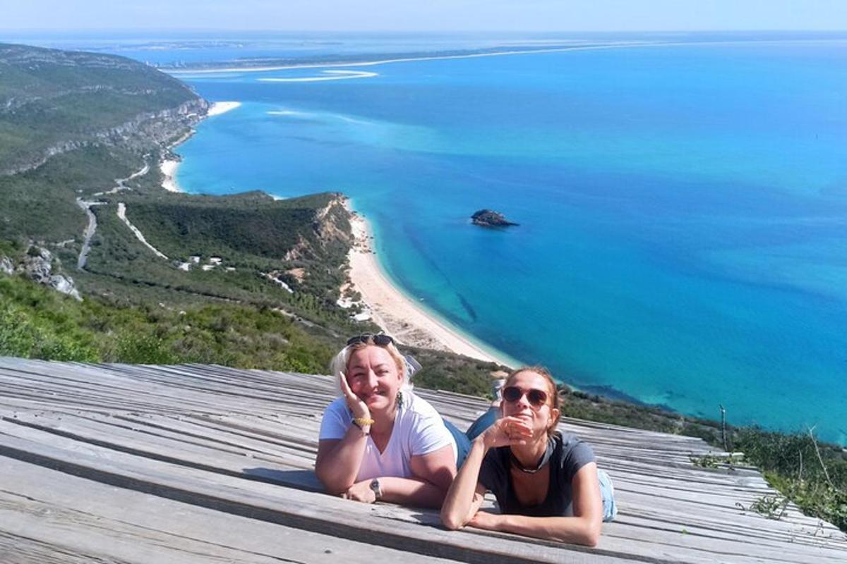 two people sitting on top of a mountain overlooking the ocean