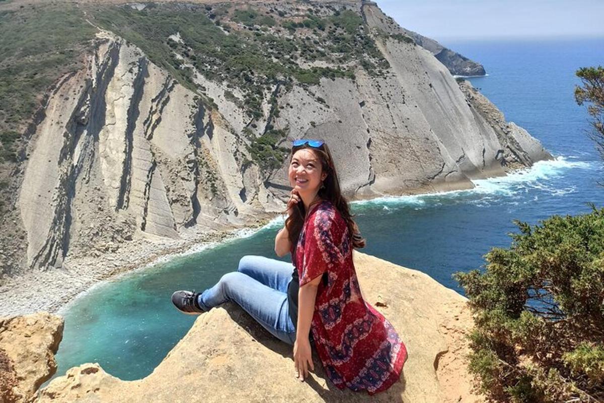 a woman sitting on a rock near the ocean