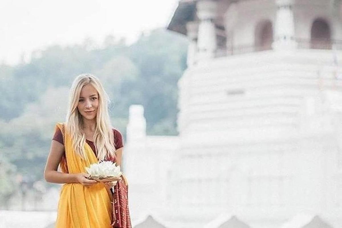 una donna in un vestito giallo che tiene in mano un mazzo di fiori