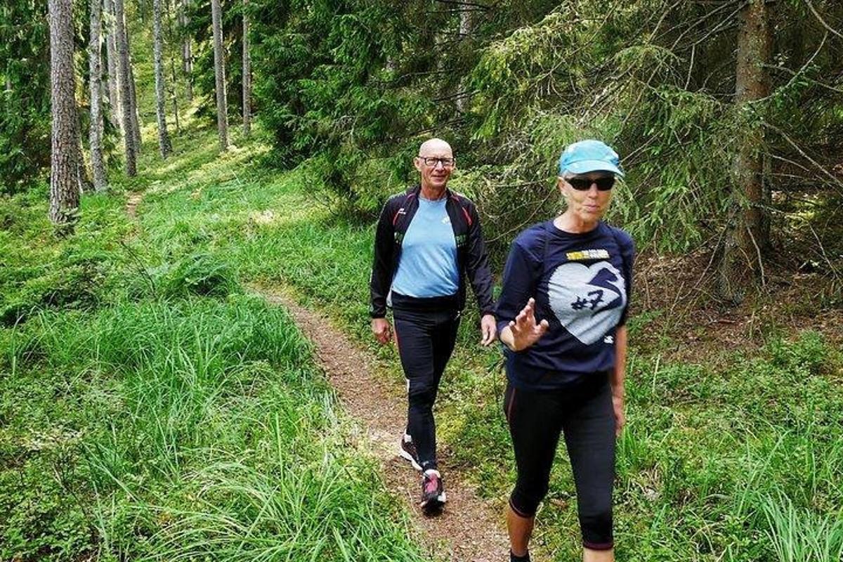 two people walking on a trail in the woods