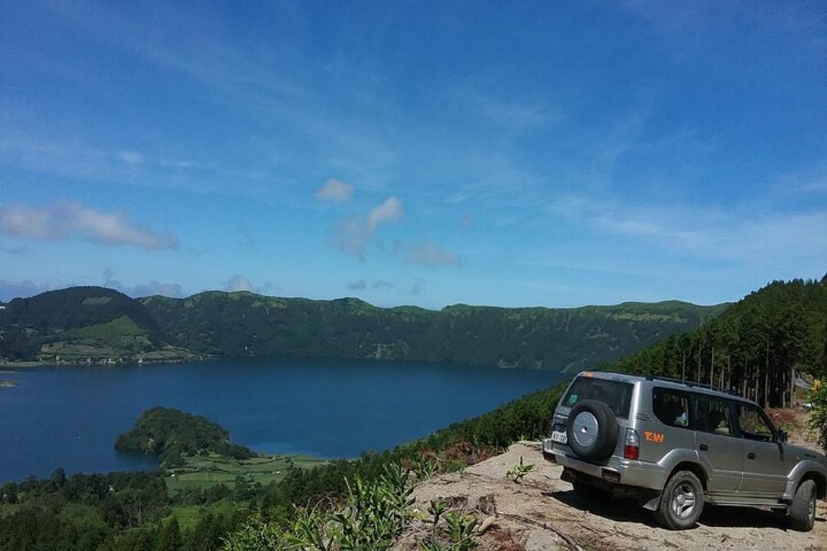 một chiếc xe jeep đậu trên một tảng đá bên cạnh một hồ nước