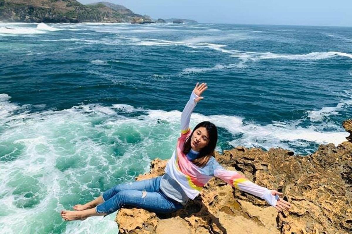 seorang wanita berbaring di atas batu di tepi lautan
