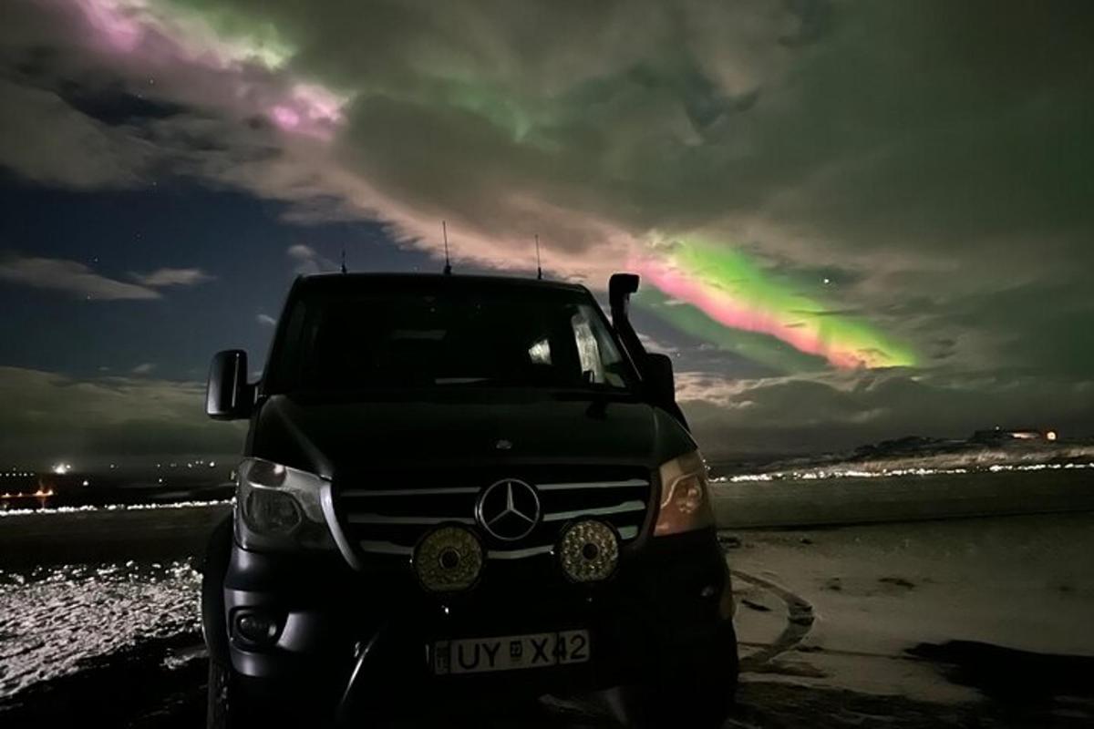 auto zaparkované na pláži s duhou na obloze