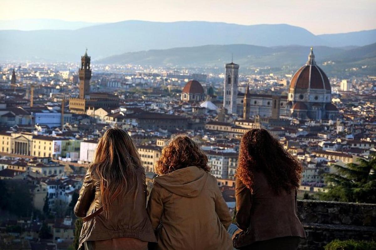 tre donne sedute in cima a una torre che guardano una città