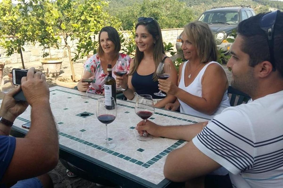 un grup de oameni așezați în jurul unei mese cu pahare de vin