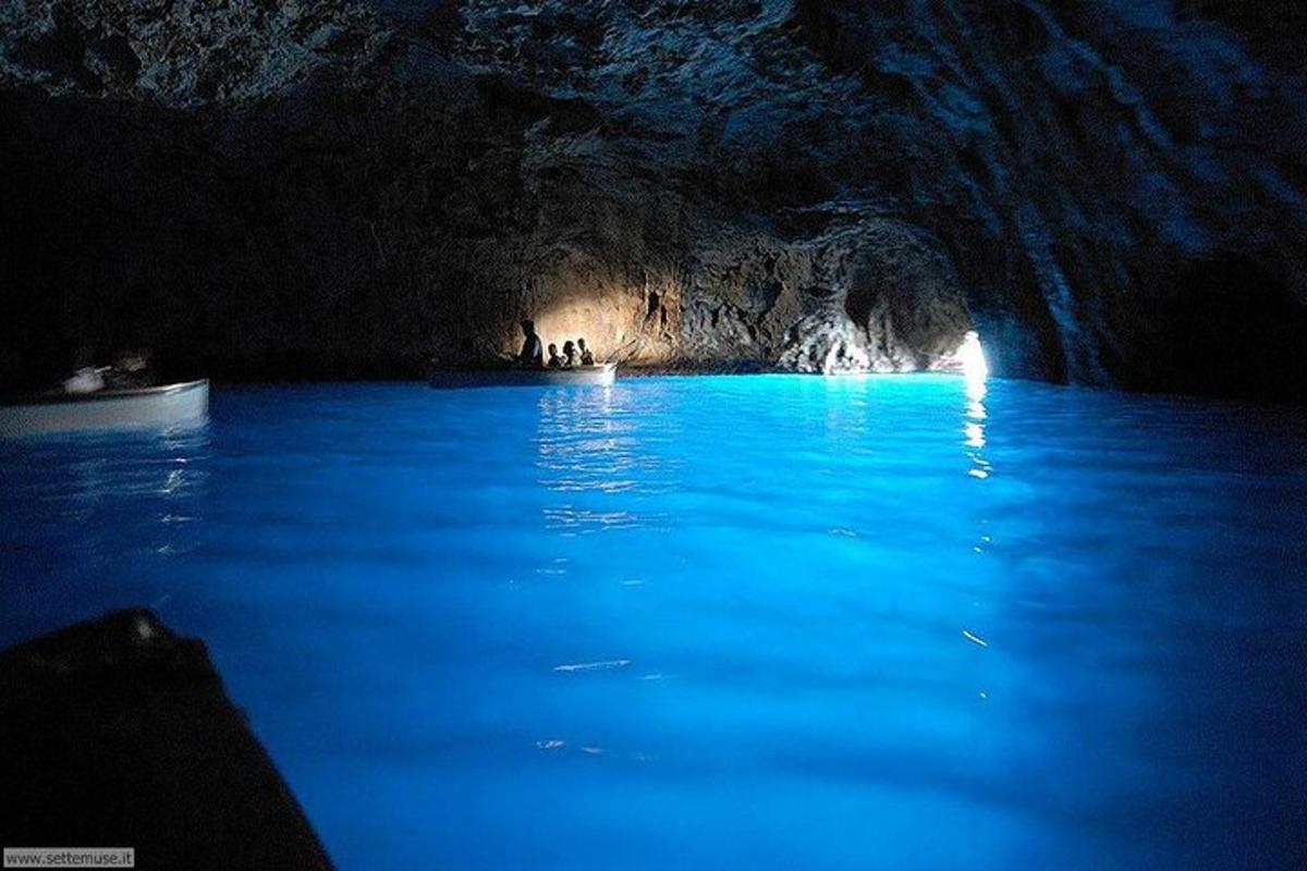 Una cueva azul con gente nadando en el agua.