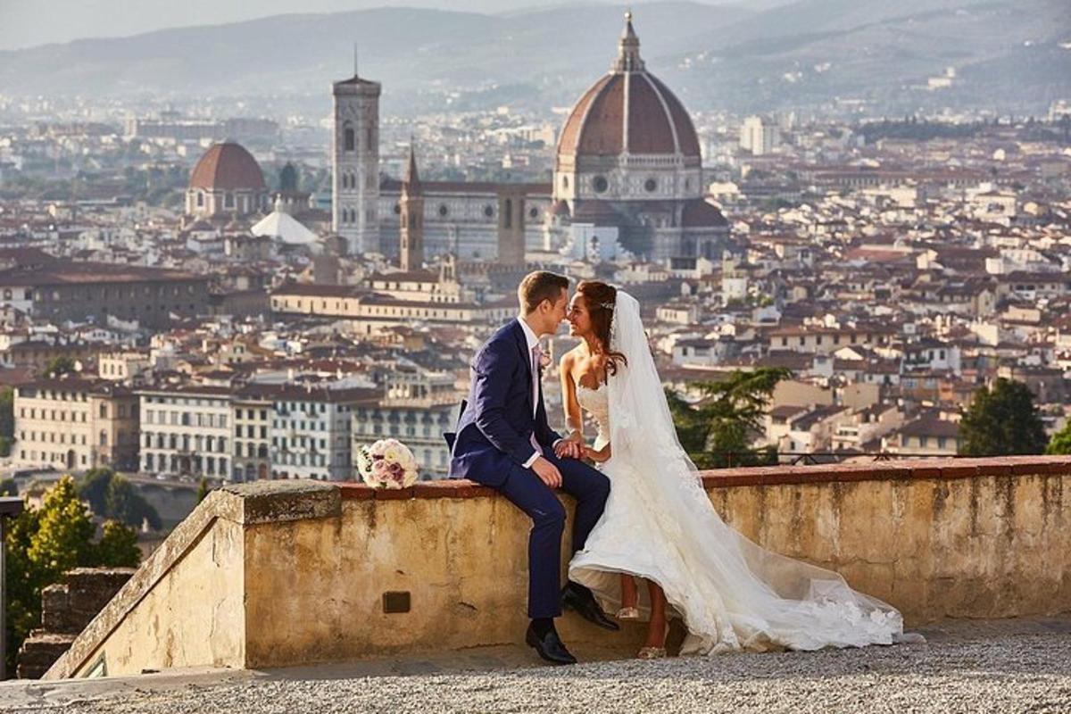 a bride and groom sitting on a wall with a view