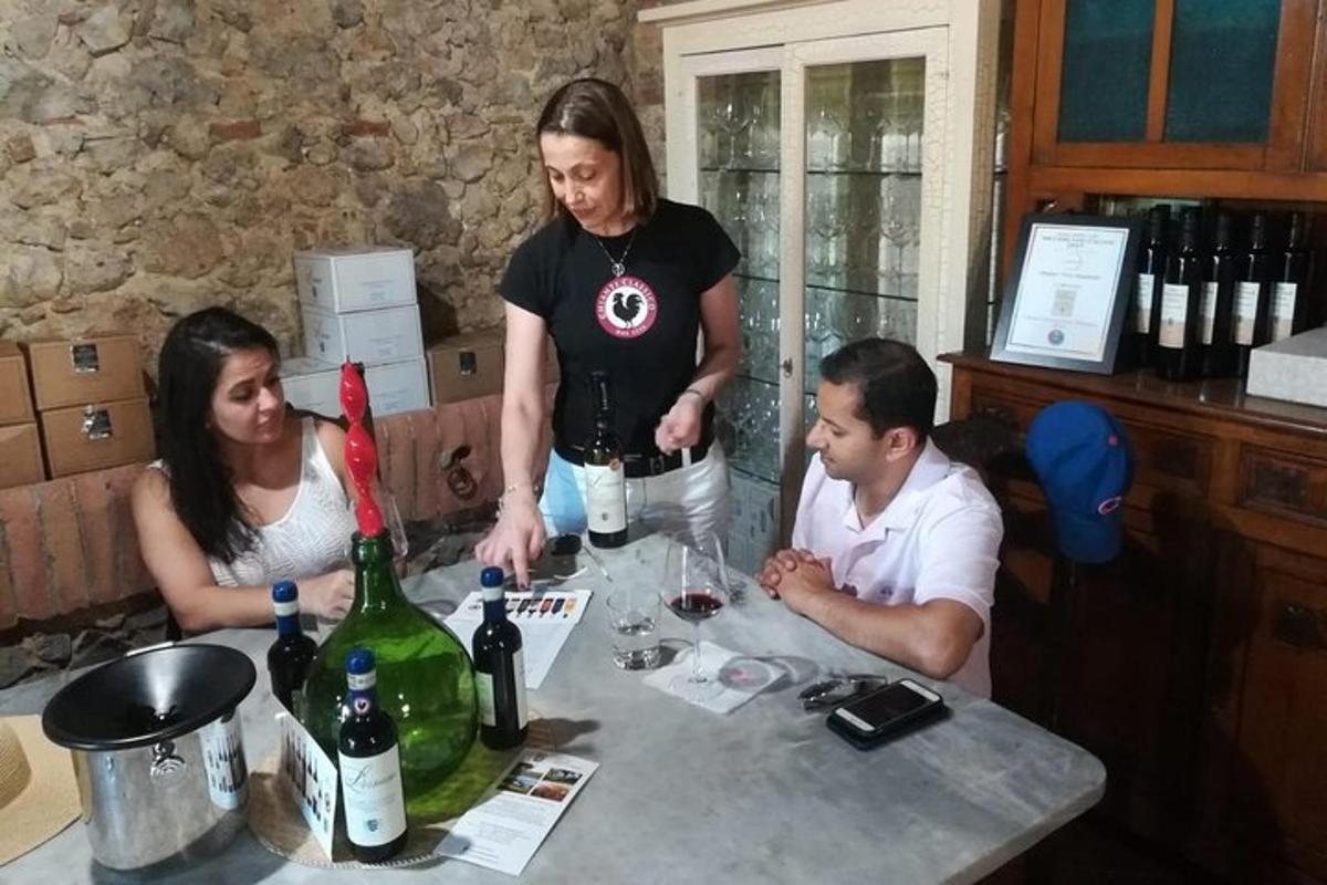 Tres personas sentadas en una mesa con botellas de vino.