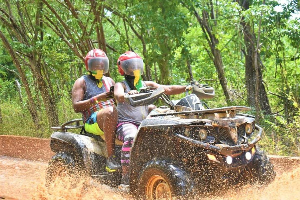 Dos personas viajando en un vehículo de cuatro ruedas en el barro.