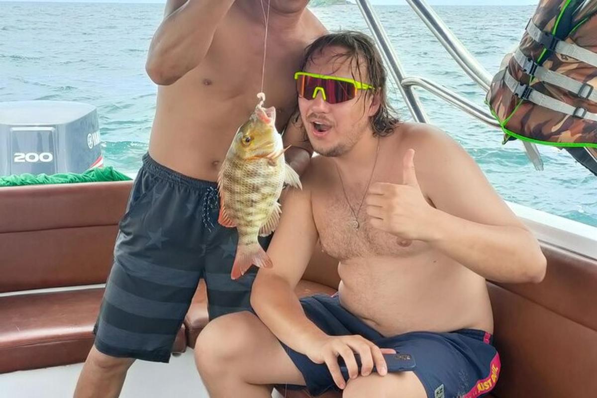 two men sitting on a boat holding a fish