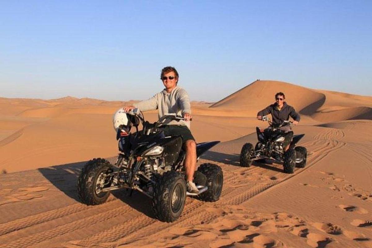 two men riding on atvs in the desert