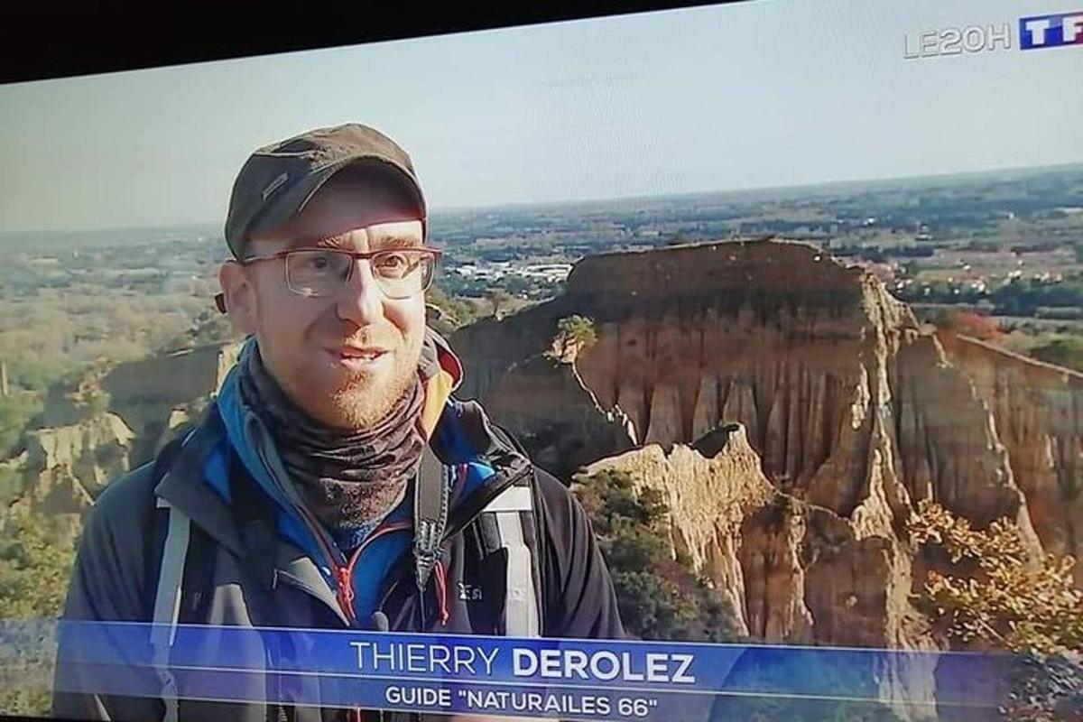 a man wearing glasses standing in front of a tv