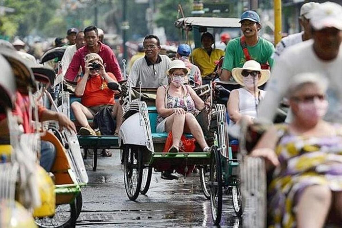 un gruppo di persone che percorrono in risciò una strada