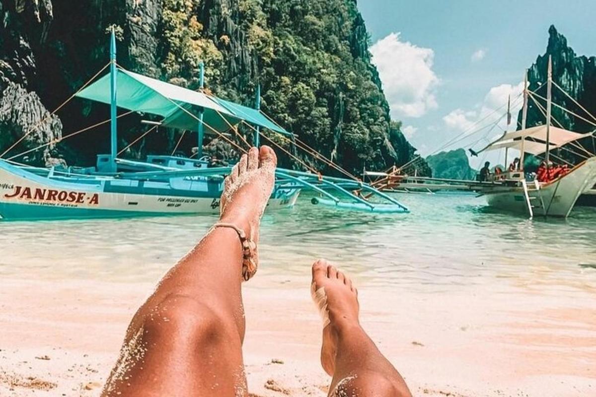a person laying on the beach with their feet in the water