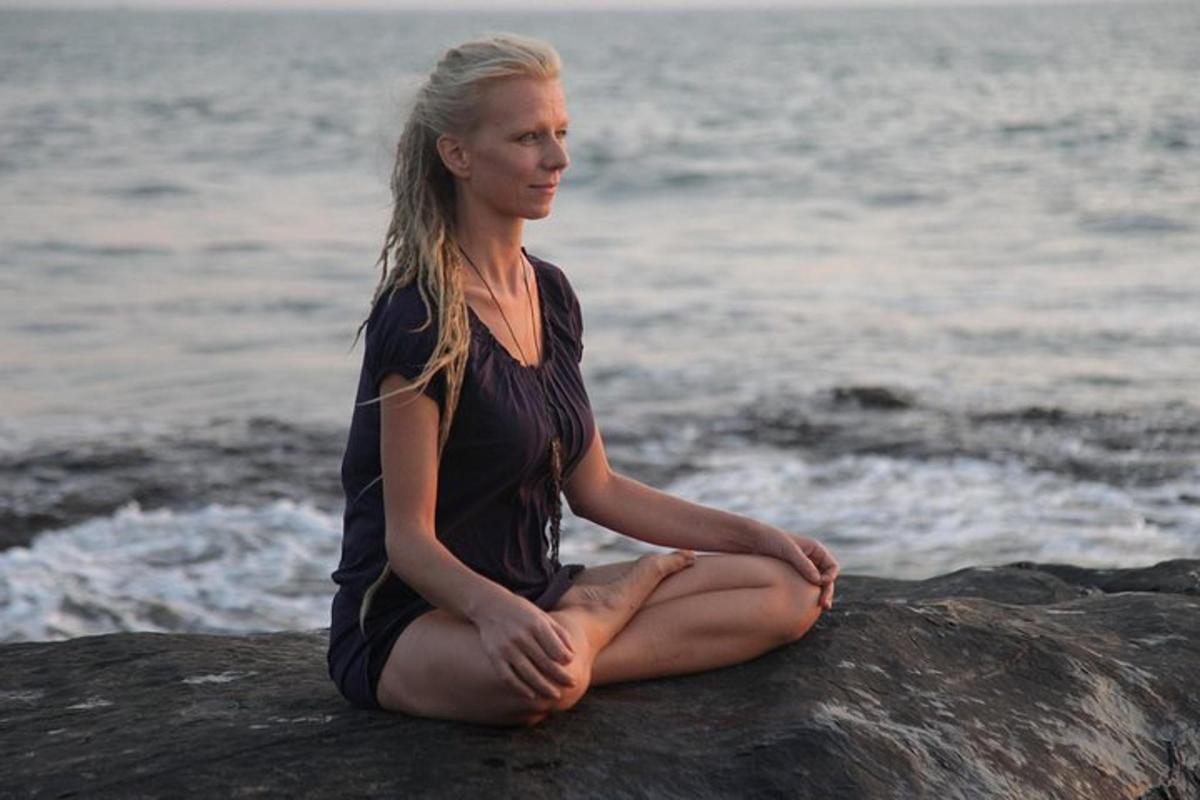 a woman sitting on a rock by the water