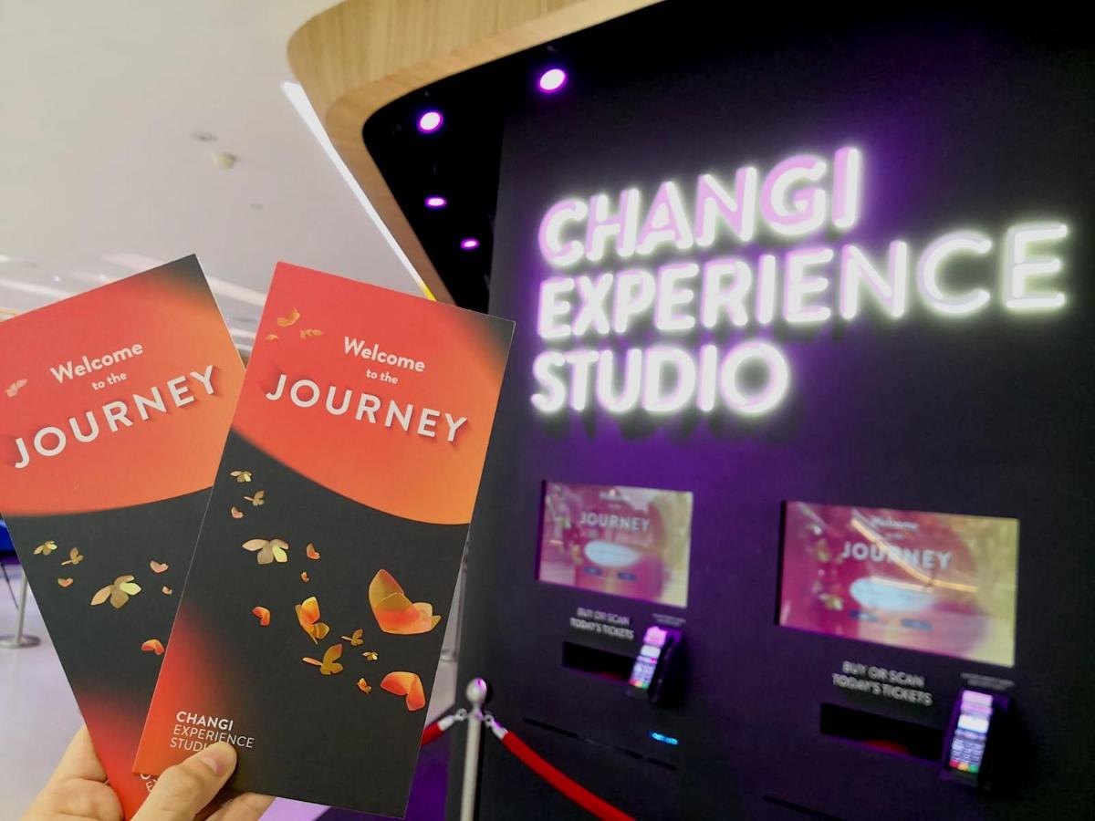 a person holding up three brochures in front of a sign