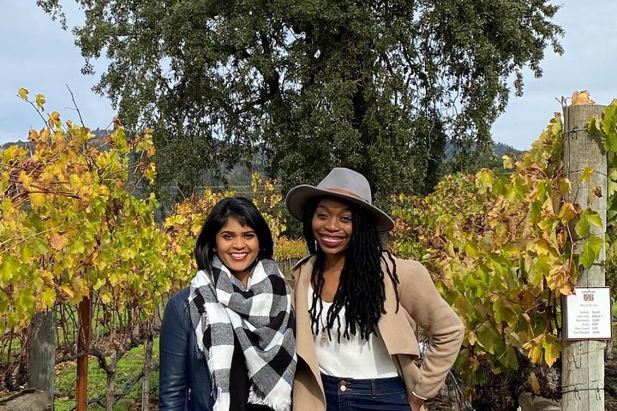 two women are standing in front of a vineyard