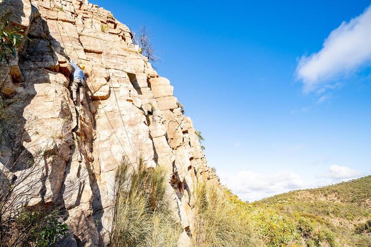 una persona che scala il fianco di una montagna rocciosa