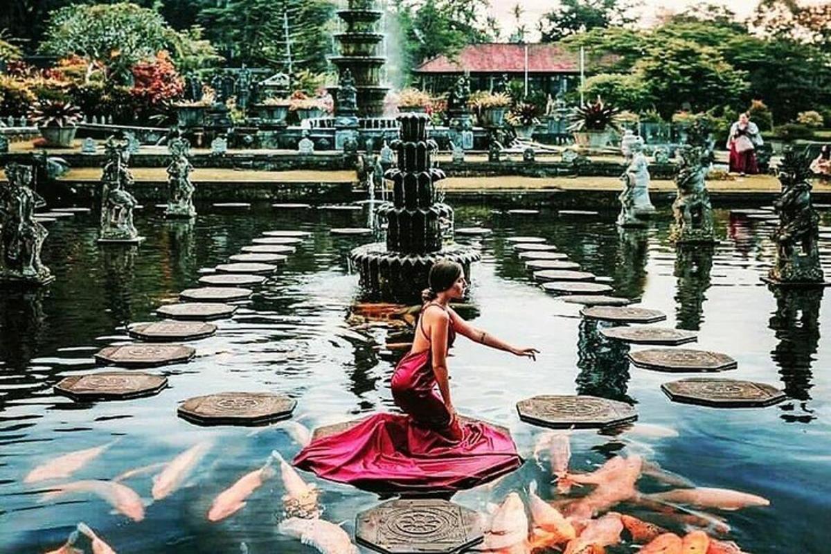 a girl in a pink dress in a pond with fish