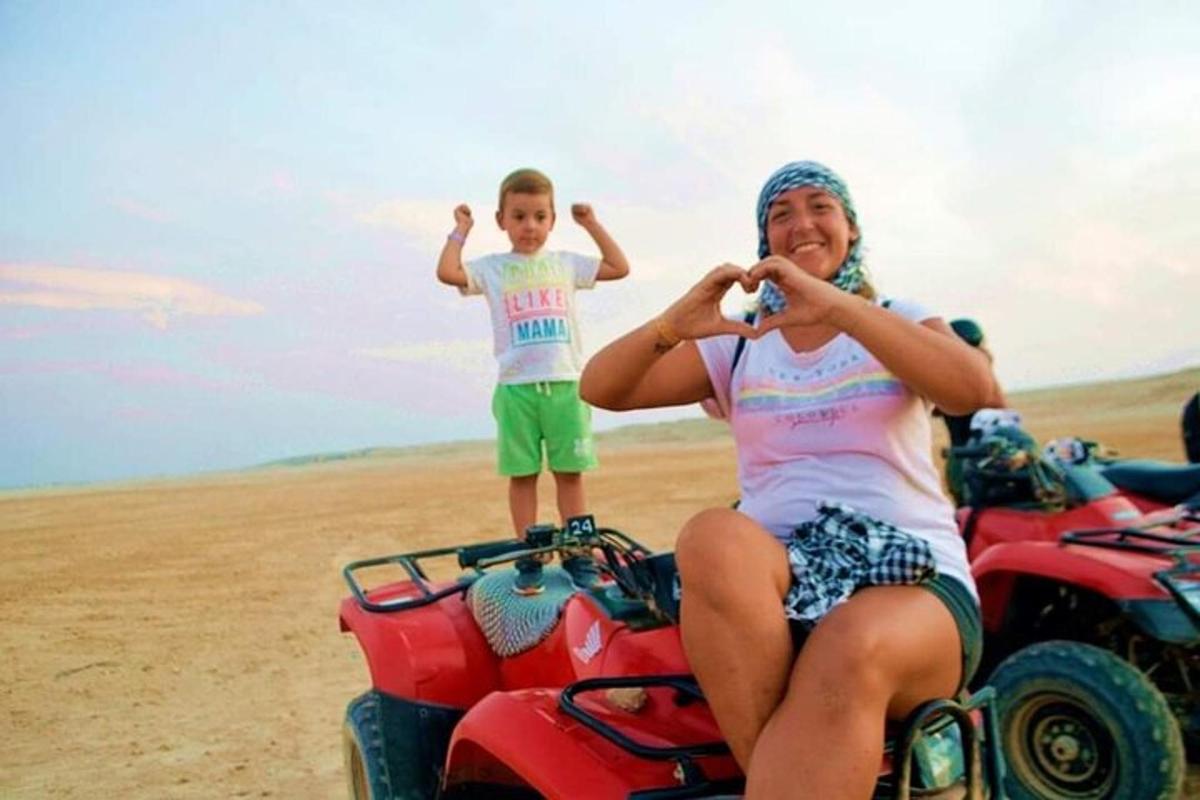 Una mujer y un niño sentados en un vehículo de cuatro ruedas en el desierto